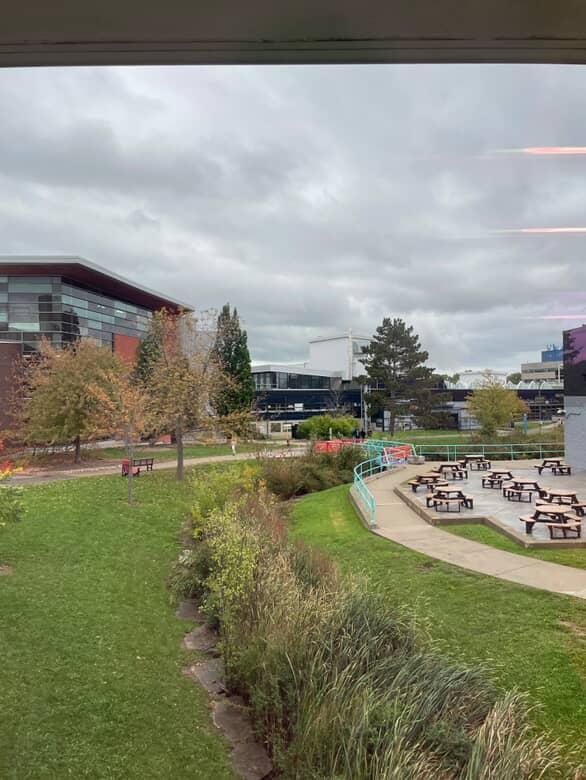 Space 3 – Outdoor Courtyard and Picnic Area (Outside SSU & Marquee)

This area’s right outside the SSU building and marquee.
It’s where people go to eat, relax, or hang out between classes.
I go here sometimes too just to chill and take a break.
Style: Natural and open.
What I see:

Wooden picnic tables
Concrete flooring
Trees, plants, and grassy areas
Teal railings that make the space look neat and defined
Overall vibe: Super chill and social and feels open and refreshing, perfect for hanging out.

